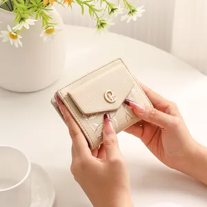Primo piano di un piccolo portafoglio in pelle PU crema con elegante logo dorato.