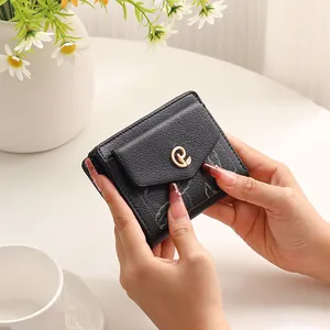 Dettaglio di un portafoglio corto nero da donna in pelle PU con logo oro e motivo
