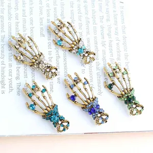 Detailed view of colorful rhinestone skeleton hand brooches displayed on a text background