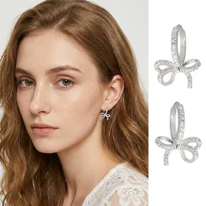 Detailed view of silver-tone bowknot hoop earrings encrusted with sparkling rhinestones