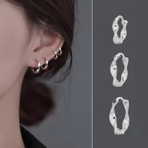 Detail view showing three silver wave pattern hoop earrings on white background
