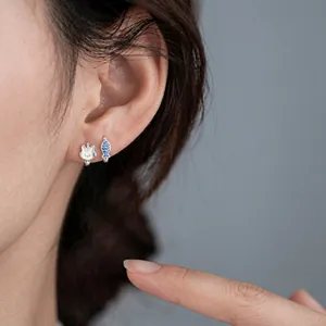 Close-up view of an Asian model wearing small silver lightning and cloud stud earrings