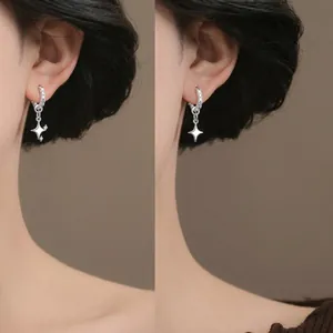 Close-up of elegant silver curved earrings with rhinestone accents on an ear.