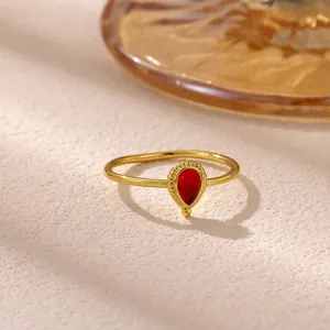 Close-up detail of a vintage style gold stainless steel ring with a red teardrop gemstone