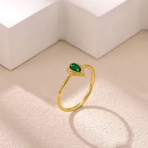 Close-up of a gold titanium steel ring with a green water-drop gemstone detail.