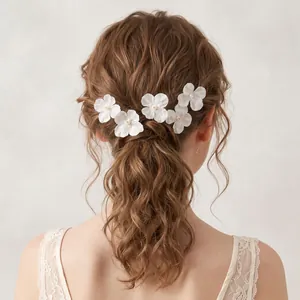 Detailansicht eleganter weißer Stoffblumen-Haarnadeln in gewelltem braunem Haar für Hochzeiten