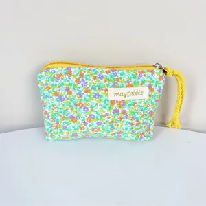 Detailed macro view of the small floral cotton pouch showing the brand label and yellow zipper