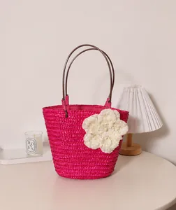 Sac cabas en paille tressée fuchsia avec détail de grande fleur crème pour la plage.