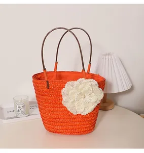 Vue détaillée du sac en paille orange orné d'une grande fleur blanche