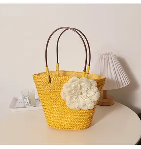 Vue détaillée d'un sac à main en paille jaune avec une grande fleur décorative