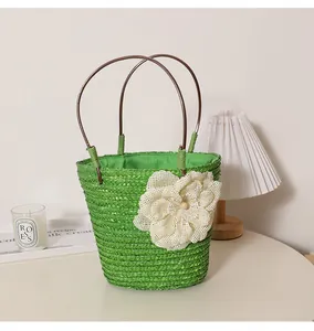 Sac cabas en paille tissé vert avec grande fleur crème pour les vacances à la plage.