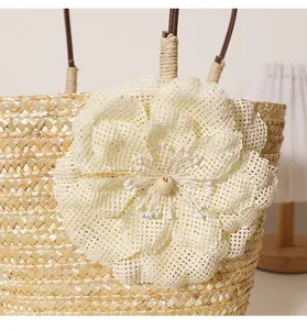 Gros plan sur le détail de la fleur tissée crème sur le sac de plage en paille.