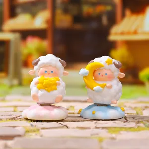 Detailed shot of cute sheep figurines with star and moon themes on a scenic background.