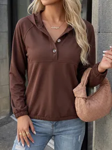Detalle de una sudadera marrón con capucha, cuello con botones y puños elásticos.