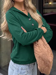 Detalle de una sudadera con capucha verde oscuro para mujer con botones marrones con textura