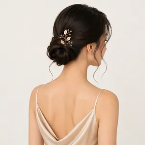 Detail shot of a handmade gold leaf and pearl hair pin styled in an elegant bridal low bun