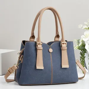 Sac à main élégant en denim bleu et cuir beige avec des détails de boucles dorées.