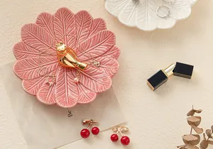 Gros plan détaillé d'un plateau à bijoux en céramique rose avec un oiseau en or.