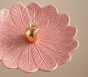Vue macro détaillée d'un plateau à bijoux en feuille de céramique rose avec glaçure lisse.