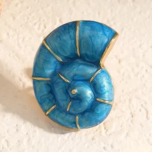 Makroansicht der Brosche aus blauem Emaille in Nautilusschalenform mit Goldrand.
