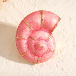 Nahaufnahme einer rosa Spiralmuschel-Brosche mit eleganten goldfarbenen Metallakzenten.