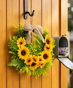 Artificial sunflower wreath with burlap bow hanging on a rustic wooden door