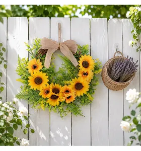Detailed view of a vibrant sunflower wreath with a burlap bow on a white garden fence
