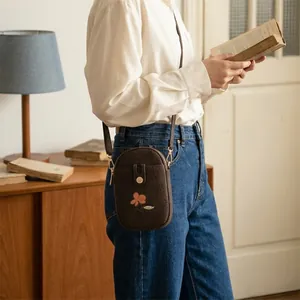 Petit sac bandoulière marron vintage avec broderie florale porté par un mannequin élégant