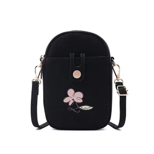 Détail frontal d'un petit sac bandoulière noir vertical avec broderie florale rose
