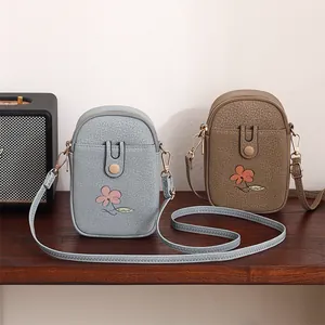 Vue détaillée de sacs à bandoulière pour téléphone bleu et marron avec motifs de fleurs.
