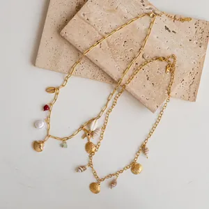 Close-up detail of stainless steel gold chain necklace with shell and starfish pendants