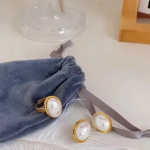Ensemble élégant de boucles d'oreilles et bague en perles sur une pochette en velours gris