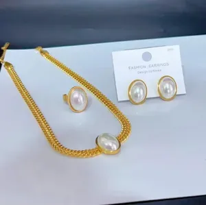 Parure de bijoux style français avec grandes perles ovales, collier doré, bague et boucles.