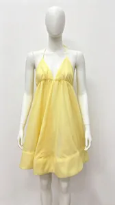 Detail of a light yellow halter backless dress with a pleated hem on a white mannequin