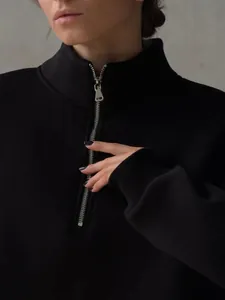 Close-up detail of a women's black half-zip oversized sweatshirt with silver zipper.