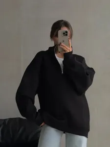 Model wearing an oversized black half-zip fleece sweatshirt in a minimalist studio