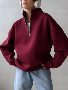 Close-up view of maroon oversized half-zip sweatshirt on model with white headphones