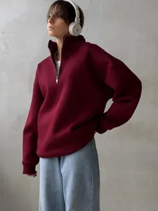 Fashion model wearing a burgundy half-zip oversize fleece sweatshirt with white headphones