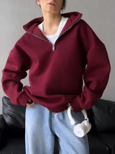 Close-up detail of a burgundy oversized half-zip fleece hoodie on a female model