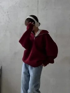 Fashion model wearing an oversized burgundy half-zip fleece hoodie in industrial setting