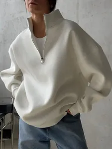 Detailed view of an oversized white half-zip sweatshirt featuring a minimalist design.