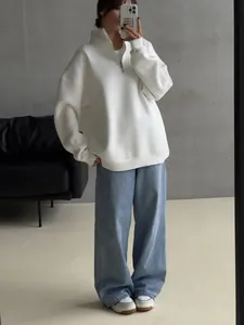Woman in white oversized half-zip fleece sweatshirt with blue wide-leg denim jeans