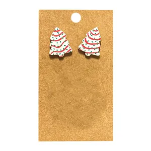 Détail de boucles d'oreilles clous en forme de sapin de Noël sur support en kraft