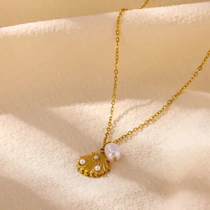 Close-up of golden shell pendant with small pearls and a baroque pearl on a gold chain.