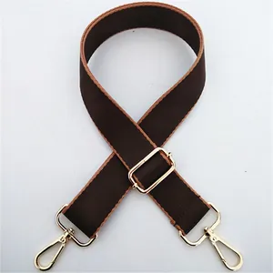Adjustable wide brown canvas bag strap with golden metal clasps and stylish tan trim