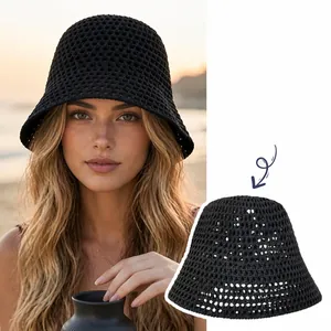 Detailed view of a black hollow-out crochet bucket hat worn by a model at the beach