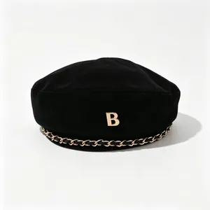 Detailaufnahme einer stilvollen schwarzen Wollbaskenmütze mit goldenem B-Logo und Kette.