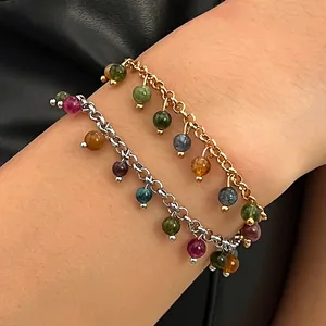 Detailed view of two multi-colored gemstone charm bracelets on a wrist.