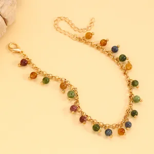 Detailed macro view of a vintage gold chain bracelet featuring colorful gemstone beads