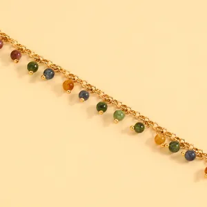 Close-up of vintage gold bracelet with colorful bead charms on a soft yellow background
